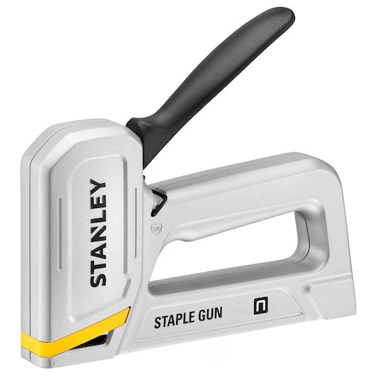 The STANLEY® Aluminium Staple Gun is a durable silver and black hand tool with yellow accents, ergonomic handle, and STANLEY branding—ideal for use as an upholstery stapler.